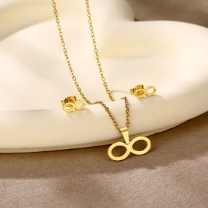 Close-up of gold infinity necklace and stud earrings set on a heart-shaped tray