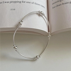 Minimalist S925 sterling silver beaded bracelet resting on an open book page