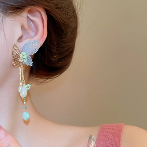 Detail of butterfly tassel earrings with pearls and crystals on a model's ear