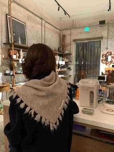 Detail view of khaki knitted scarf with tassels shown from a stylish back perspective