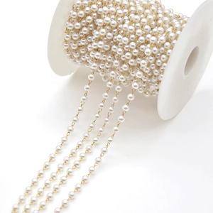 Close-up of artificial cream pearl chain on gold spool for jewelry DIY making