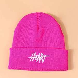Close-up of bright pink knitted beanie with white HEART embroidered lettering detail