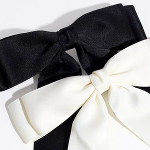 Detailed close-up of large black and white satin bow clips with elegant ribbon texture