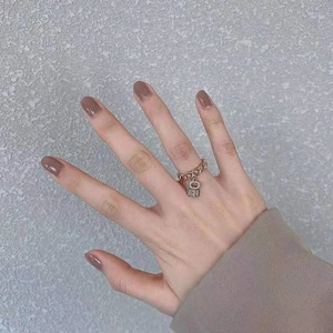 Gros plan d'une bague chaîne en or rose avec un pendentif cadenas serti sur le doigt