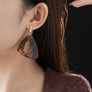 Detail of dark brown tortoiseshell resin earring with a hollow triangle dangle design