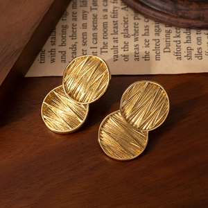 Gold titanium steel earrings with double layered sunburst texture discs on dark wood