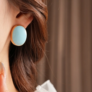 Close-up of vintage oval light blue enamel earring with a refined golden metal frame
