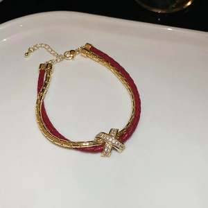 Gros plan d'un bracelet double couche en cuir rouge avec pendentif X en zircon doré