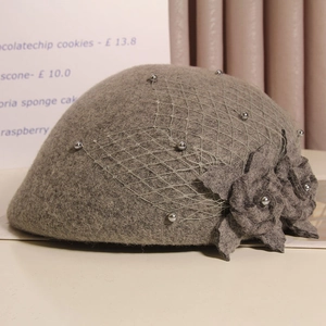 Detail of grey wool beret with fabric flower, mesh veil and pearl accents
