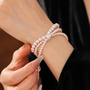 Close-up of triple-strand pearl bracelet with zircon clasp worn on female wrist