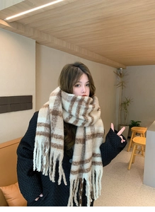 Detail of soft beige and brown plaid scarf with thick fringe on a model in a cafe