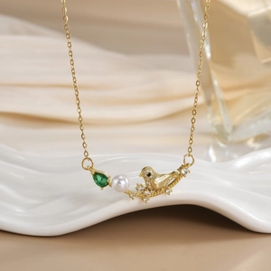 Detail of bird pendant necklace with pearl and emerald drop gemstone in gold finish