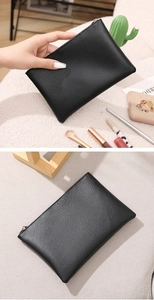 Close-up of black lychee grain leather makeup bag with silver zipper and lifestyle props