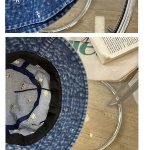 Detail of blue denim bucket hat showing white daisy embroidery and internal texture