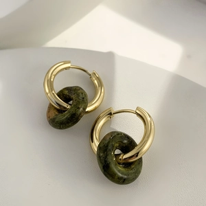Detailed macro of gold plated hoop earring with dark green natural stone pendant