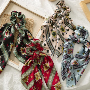 Flat lay of vintage patterned satin ponytail scarves in black, red, beige and blue