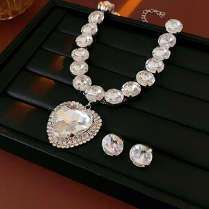 Detailed shot of luxurious silver heart necklace and round stud earrings set with large crystals