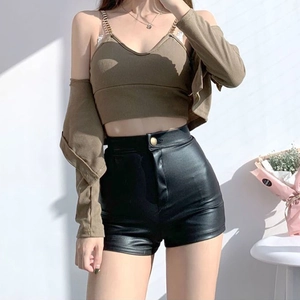 Detail der schwarzen PU-Leder-Shorts mit hoher Taille und beigefarbenem Strick-Set
