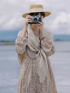 Detail of a creamy chunky knit shawl paired with a floral dress and a woven straw hat