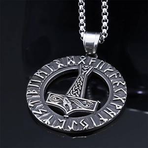 Close-up of a Viking Mjolnir pendant with runes and axe details on a polished black surface