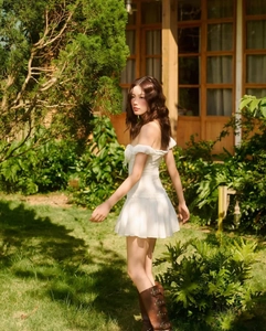Side view of white off-the-shoulder French retro mini dress in a forest setting