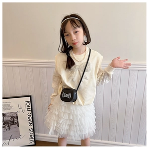 Close-up of a child's black crossbody bag featuring a large pearl and bow embellishment