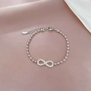 Macro detail of silver infinity bracelet with sparkling crystals on silk background