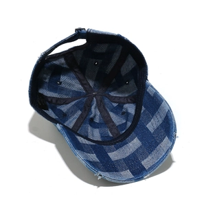 Detail of blue and white checkered denim baseball cap with distressed brim and inner strap