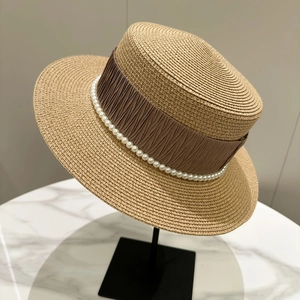 Detailed view of boater hat with brown pleated ribbon and elegant pearl embellishments