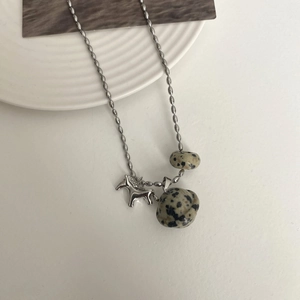 Detailed shot of tiger eye stone necklace with horse pendant on a white ceramic plate