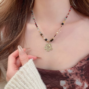Close-up of a colorful beaded necklace with a golden four-petal flower Fu pendant