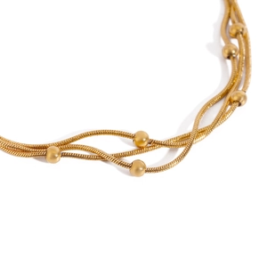 Layered gold stainless steel snake chain bracelet with elegant metallic beads on white background