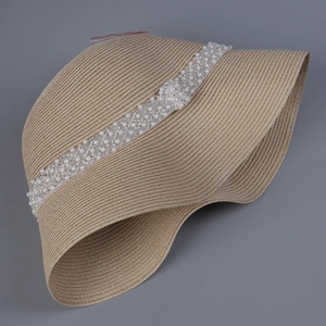 Detailansicht eines beigen Strohhutes mit elegantem Perlenband-Dekor für Damen