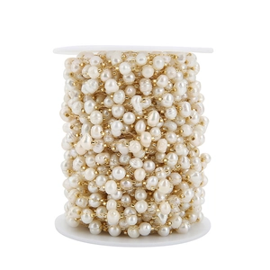 Macro view of 5-7mm natural pearls and 18k gold-plated beads on a white plastic spool