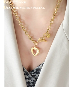 Detailed close-up of a French style 18k gold heart pendant necklace with trendy OT buckle