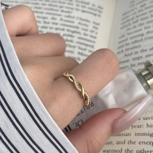 Macro shot of gold twist rope ring with zircon inlay worn in an elegant lifestyle setting