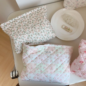 Vue détaillée des trousses à maquillage en coton matelassé avec motifs floraux et zip