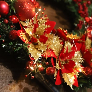 Christmas wreath with red poinsettia flowers, golden leaves, and warm LED string lights