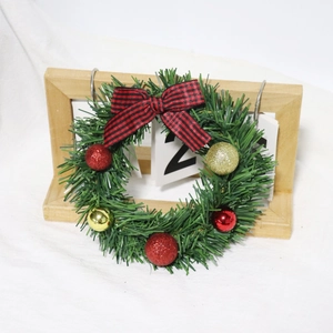 Mini Christmas wreath with plaid bow and festive red gold balls on white fabric