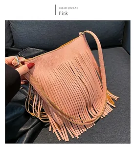 Detailed view of pink pebble grain bucket bag featuring long tassel fringes and silver hardware