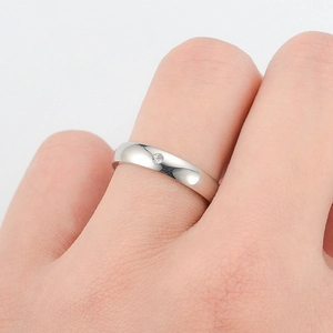 Close-up of a minimalist silver titanium steel ring with a single diamond inlay on a finger