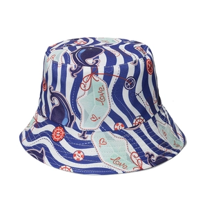 Close-up of ocean-themed prints with whales and rudders on blue-white striped bucket hat