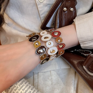 Detail of colorful enamel patchwork bracelets on wrist with urban chic fashion style