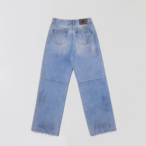 Détail du jean denim bleu clair délavé montrant les poches arrière et l'écusson croix