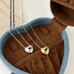Golden and silver spiral textured heart necklaces displayed in a heart-shaped jewelry box