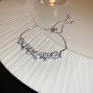 Detail of adjustable silver bracelet featuring five shimmering heart-shaped zircons