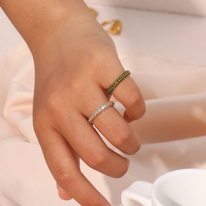 Close-up of gold-plated rings featuring sparkling green and white zircon gemstones