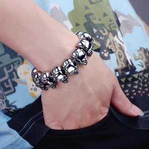 Detailed view of skull link bracelet in polished stainless steel on a male wrist