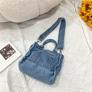 Detailed view of blue denim handbag with ruffled sides and detachable shoulder strap