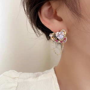 Gros plan sur des boucles d'oreilles cœur vintage avec zircons, perles et glands dorés